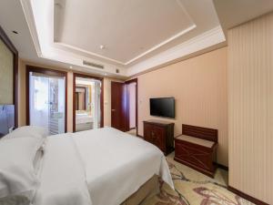 una camera con un grande letto e una televisione di Vienna Classic Hotel Shizhongshan Avenue a Jiujiang