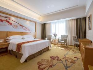 a hotel room with a large bed and a desk at Vienna International Hotel Shenzhen Bantian Jihua Road Shangxue in Longgang