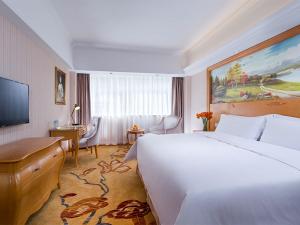 una camera d'albergo con un grande letto e una scrivania di Vienna Hotel Shenzhen Lo Wu Control Point a Shenzhen