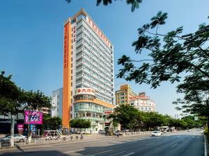 wysoki budynek przy ulicy miejskiej w obiekcie Vienna Hotel Foshan Nanhai Avenue Branch w mieście Foshan