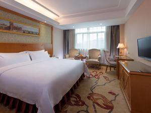 um quarto de hotel com uma cama grande e uma televisão em Vienna 3 Best Hotel Shenzhen Henggang Cuihu Shangzhuang em Longgang