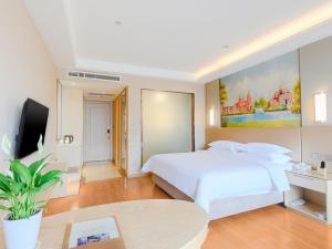 una camera con un grande letto bianco e una TV di Vienna International Hotel Hengyang Chuanshan Road Branch ad Hengyang