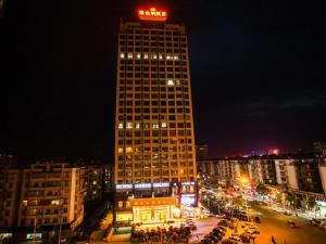 a tall building with a neon sign on top of it at Vienna Hotel Jiangxi Yichun City Hall in Yichun