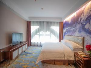 a bedroom with a bed and a tv and a painting at Venus royal hotel(Keyuan Guancheng Dongguan) in Dongguan