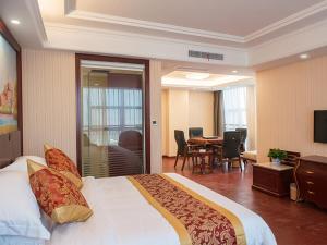 a hotel room with a large bed and a dining room at Vienna Hotel Zhejiang Huzhou Changxing Mingzhu Road in Changxing +2 photos
