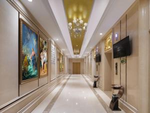 einen Flur mit Gemälden an den Wänden und einem Kronleuchter in der Unterkunft Vienna International Hotel Nanchang Xinjian Center in Nanchang