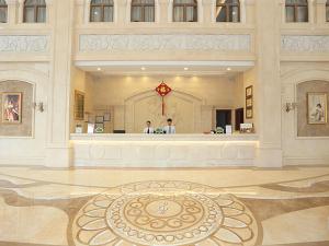 two people standing in a large building with a counter at Vienna Hotel Shantou Longhu South Taishan Road in Shantou