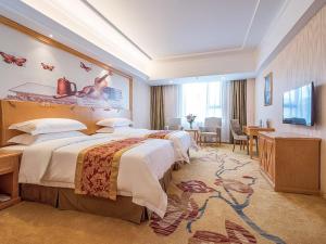 a hotel room with two beds and a television at Vienna International Hotel Shenzhen Bantian Jihua Road Shangxue in Longgang