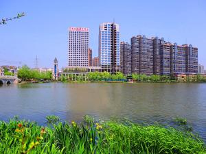 une masse d'eau avec de grands bâtiments et une ville dans l'établissement Vienna Hotel Hubei Tianmen Donghu International, à Tianmen