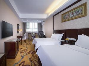 una camera d'albergo con due letti e una televisione di Vienna Hotel Shenzhen Shangjin Center a Bao'an