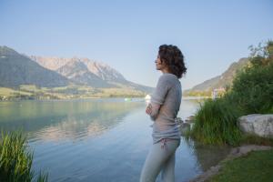 una mujer parada frente a un cuerpo de agua en Seehotel Brunner en Walchsee