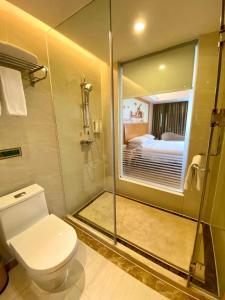 a bathroom with a toilet and a shower and a bed at Vienna International Hotel Guangdong Foshan Shunde Ronggui in Shunde