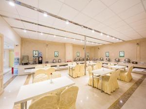 ein großes Zimmer mit Tischen und Stühlen und eine Cafeteria in der Unterkunft Vienna international hotel shanghai pudong airport south store in Huinan