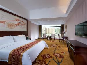 a hotel room with a large bed and a desk at Vienna International Hotel Jieyang Jieyanglou in Jieyang