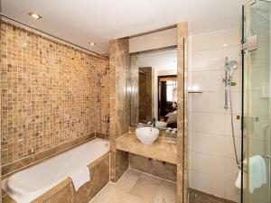 Vienna Hotel Zhaoqing Qixingyanpaifang في زاوشينغ: حمام مع حوض استحمام ومغسلة
