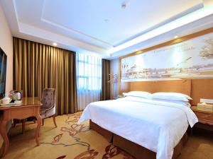 een hotelkamer met een groot bed en een bureau bij Vienna Classic Hotel Shenzhen Bantian Wuhe Avenue in Shenzhen
