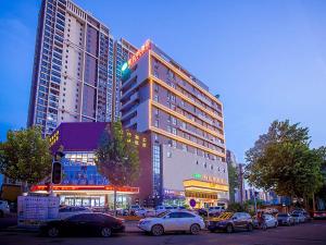 un edificio alto con coches estacionados en un estacionamiento en Vienna Hotel Whhan xingye road stone bridge subway station store, en Wuhan