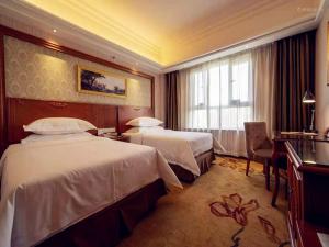 a hotel room with two beds and a desk at Vienna Hotel Xinjiang Yining Shanghai City in Yining