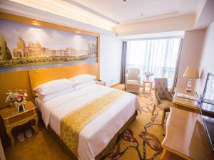 a bedroom with a large bed and a painting on the wall at Vienna Hotel Guangdong Huizhou Jiangbei Sanxin in Huizhou