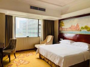 a hotel room with a bed and a large window at Vienna Hotel Foshan Nanhai City Square in Foshan