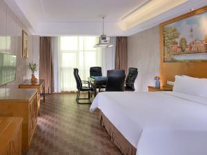 a hotel room with a bed and a table and chairs at Vienna Hotel HaiNan Oriental Avenue in Dongfang