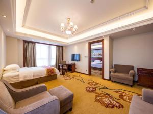 ChunshenにあるVienna International Hotel Shanghai Hongqiao Exibition Central Xinqiaoのベッド、ソファ、椅子が備わるホテルルームです。