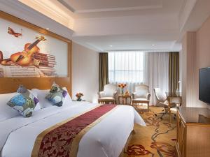 a hotel room with a large bed with a guitar on the wall at Vienna Hotel Shenzhen Fuyong Subway Station in Bao'an