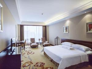 a hotel room with a large bed and a desk at Vienna International Hotel Shenzhen Hua'nan City in Longgang