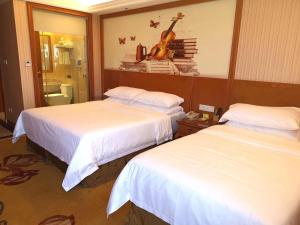 a hotel room with two beds and a guitar on the wall at Vienna International Hotel Hangzhou Zhuantang Art School in Wenyan +5 photos