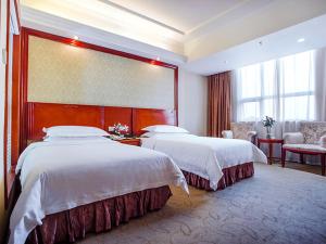 Habitación de hotel con 2 camas y ventana grande. en Vienna International Hotel Shenzhen Songgang Wanzhao Square, en Bao'an