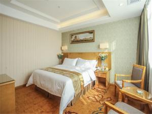 a hotel room with a large bed and a table at Vienna Hotel Fuzhou Linchuan Avenue in Fuzhou +8 photos