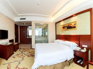 a bedroom with a large white bed and a television at Vienna Hotel Foshan Jihua Road in Foshan