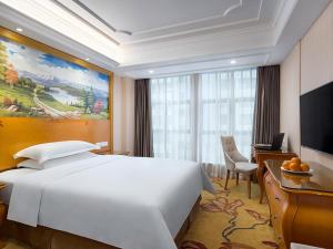 um quarto de hotel com uma grande cama branca e uma secretária em Vienna Hotel Changsha Gaoxin Lugu Park em Changsha