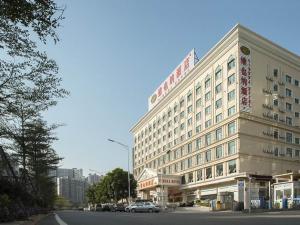 Vienna Hotel Shenzhen Longhua South Renmin Road في باوان: مبنى كبير فيه سيارة متوقفة أمامه
