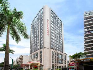 a tall building in a city with a palm tree at Vienna Hotel Guangdong Huizhou Jiangbei Sanxin in Huizhou
