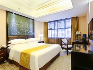 um quarto de hotel com uma cama grande e uma janela em Vienna Hotel Changsha Gaoxin Lugu Park em Changsha