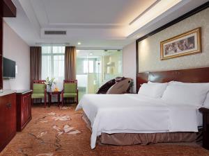 a hotel room with a large bed and a dining room at Vienna Hotel Huizhou Zhongxin in Huizhou
