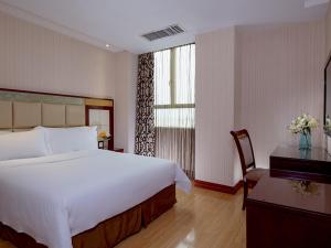 a bedroom with a large white bed and a desk at Vienna Hotel in Pinghu Square in Longgang