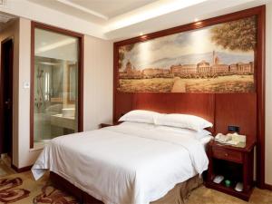 1 dormitorio con 1 cama grande y una pintura en la pared en Vienna Hotel Jiefang East Road en Wuxi