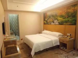 1 dormitorio con 1 cama y una pintura en la pared en Vienna Hotel Dongguan Tangxia Lincun Square, en Dongguan