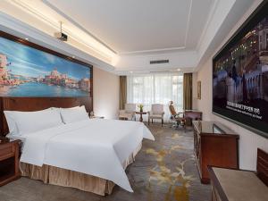 Habitación de hotel con cama blanca grande y TV. en Vienna Hotel Foshan Huangqi, en Nanhai
