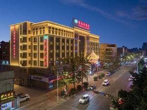 ein großes Gebäude mit Neonschildern an einer Stadtstraße in der Unterkunft Vienna Hotel Foshan Huangqi in Nanhai