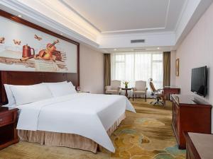 ein Hotelzimmer mit einem großen Bett und einem TV in der Unterkunft Vienna Hotel Foshan Huangqi in Nanhai