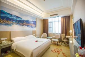 a hotel room with a large bed and a tv at Vienna Hotel Nanyang People Road in Nanyang