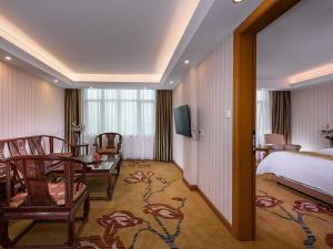 ein Hotelzimmer mit einem Bett, einem Tisch und Stühlen in der Unterkunft Vienna Hotel (Jieyang Jinxian Dadao Shop) in Jieyang