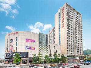 un grand bâtiment avec des voitures garées dans un parking dans l'établissement Vienna International Hotel Huizhou Daya Bay Century City, à Huizhou