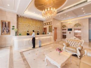 a man standing at a counter in a hotel lobby at Vienna Hotel Shenzhen Baoneng City Plaza in Longgang