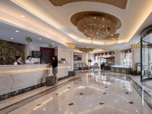 un vestíbulo de un hotel con gente parada en un mostrador en Vienna International Hotel Changzhou Hutang en Changzhou
