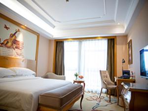 XuanzhouにあるVienna International Hotel Xuancheng Gardenのベッドと大きな窓があるホテルの部屋