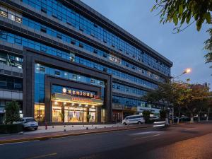 a large building with cars parked in front of it at Vienna Hotel(Xiamen Airport Xianmen Drum Whart) in Xiamen